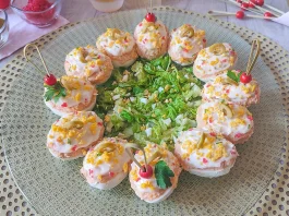 Huevos rellenos de atún, tomate y mayonesa decorados con aceitunas en una fuente