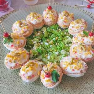 Huevos rellenos de atún, tomate y mayonesa decorados con aceitunas en una fuente