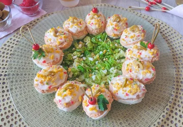 Huevos rellenos de atún, tomate y mayonesa decorados con aceitunas en una fuente