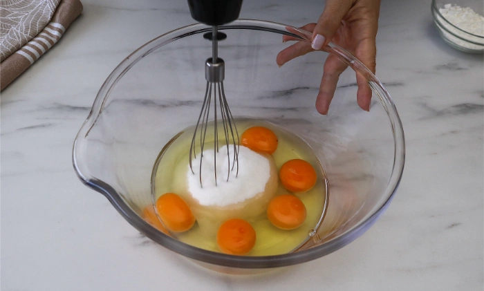 Huevos y azúcar en un bol para empezar a elaborar un bizcocho genovés