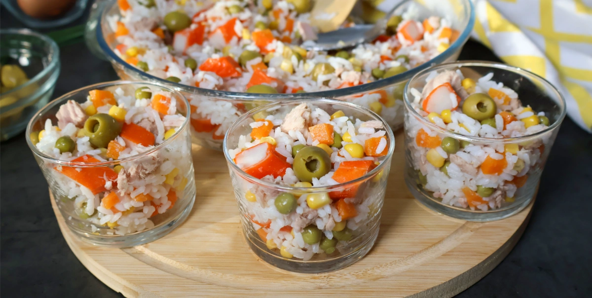 Ensalada de arroz con atún, guisantes, maíz, zanahoria y aceitunas servida en vasitos individuales