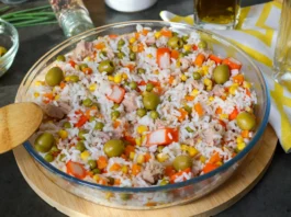 Ensalada de arroz con atún, guisantes, maíz, zanahoria, surimi y aceitunas en una fuente