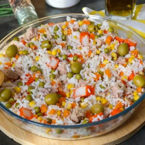 Ensalada de arroz con atún, guisantes, maíz, zanahoria, surimi y aceitunas en una fuente