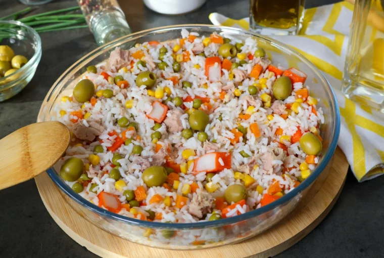Ensalada de arroz con atún, guisantes, maíz, zanahoria, surimi y aceitunas en una fuente