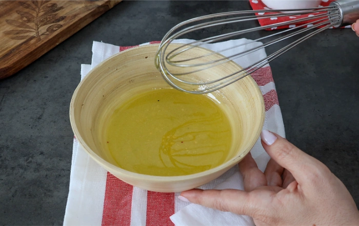 Vinagreta de aceite y vinagre batida con varillas en un bol para la ensalada de arroz