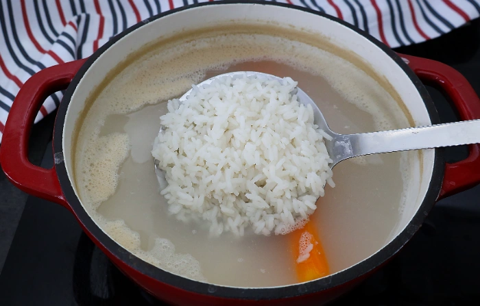 Arroz cociéndose en una olla, recogido con una espumadera para ver el punto de cocción
