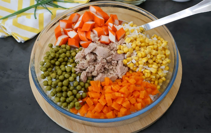 Bol con arroz, atún, guisantes, maíz, zanahoria y surimi antes de mezclar la ensalada