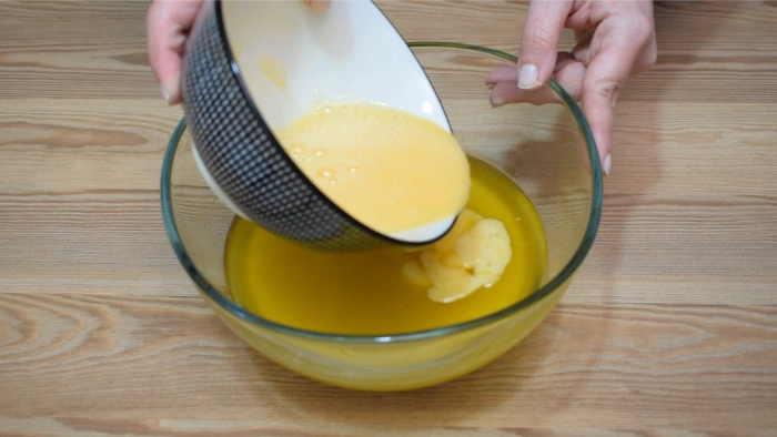 Añadiendo los huevos batidos a la mezcla de aceite, vino y manteca para la masa del hornazo de Salamanca