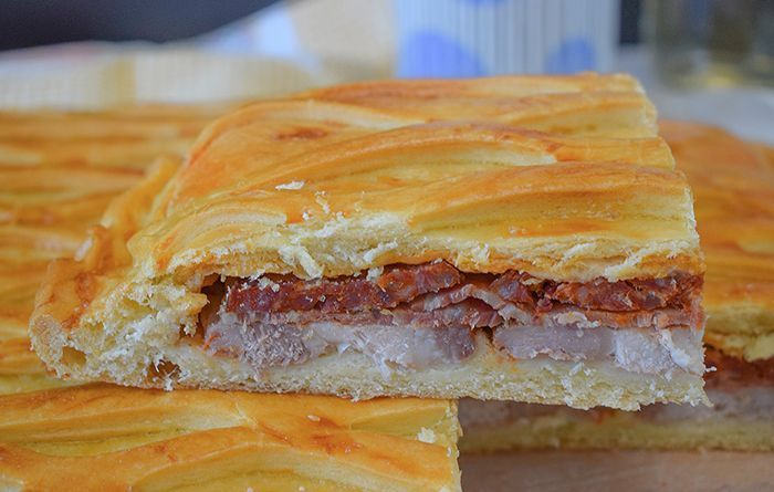 Hornazo de Salamanca cortado mostrando las capas de relleno con lomo de cerdo, jamón y chorizo bajo la masa dorada con rejilla