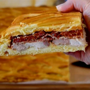 Porción de hornazo de Salamanca casero mostrando las capas de lomo, jamón y chorizo entre la masa dorada con rejilla