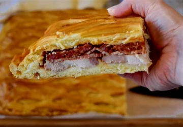 Porción de hornazo de Salamanca casero mostrando las capas de lomo, jamón y chorizo entre la masa dorada con rejilla