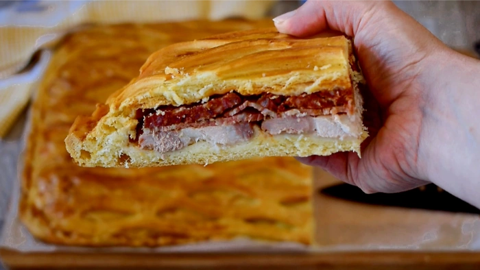 Porción de hornazo de Salamanca casero mostrando las capas de lomo, jamón y chorizo entre la masa dorada con rejilla