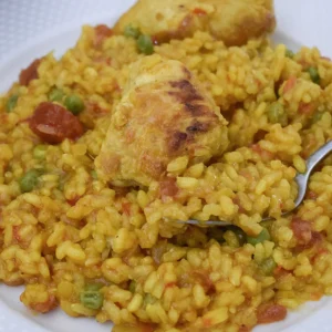 Primer plano del arroz con pollo y verduras en una cuchara, mostrando su textura melosa .