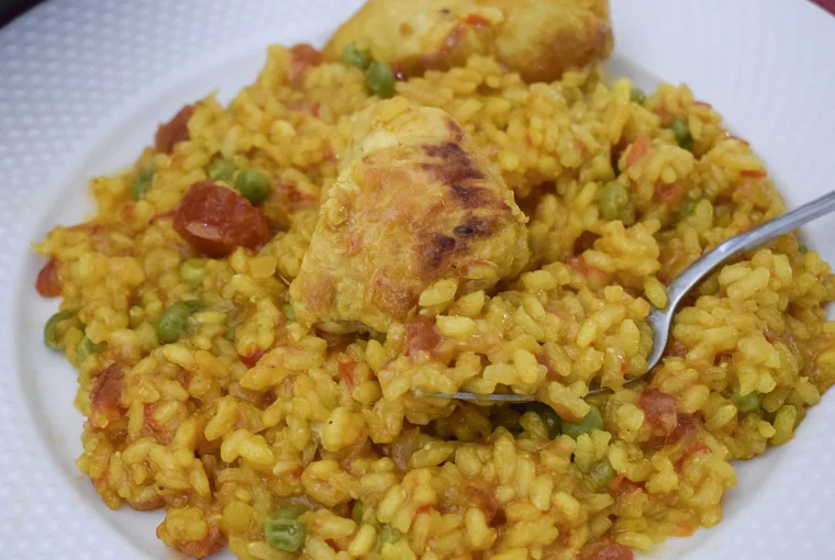 Primer plano del arroz con pollo y verduras en una cuchara, mostrando su textura melosa .