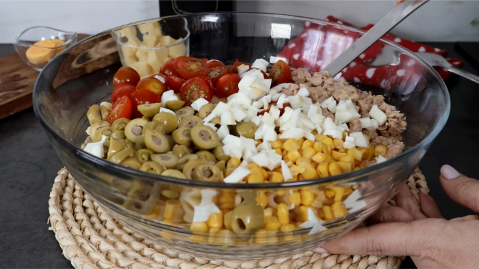 Bol con macarrones, atún, maíz, cherrys, aceitunas y huevo picado antes de mezclar