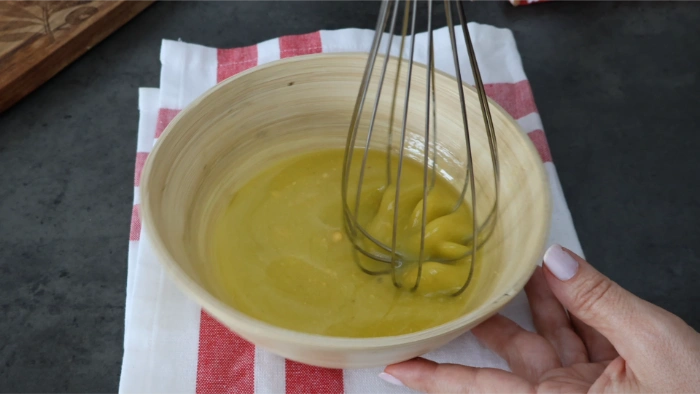 Vinagreta cremosa emulsionada con yema de huevo batida con varillas en un bol