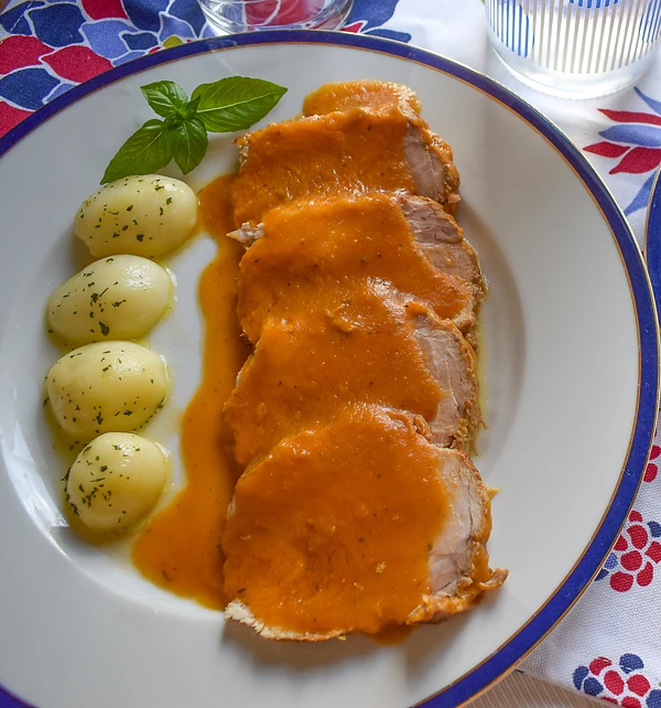 Lomo de cerdo fileteado con salsa de verduras y patatas cocidas