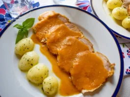Lomo de cerdo en salsa con patatas cocidas servido en plato blanco