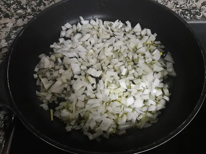 Cebolleta picada cocinándose en sartén con aceite