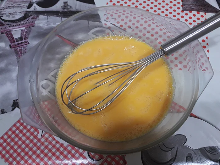 Huevos batidos en bol con varilla de cocina