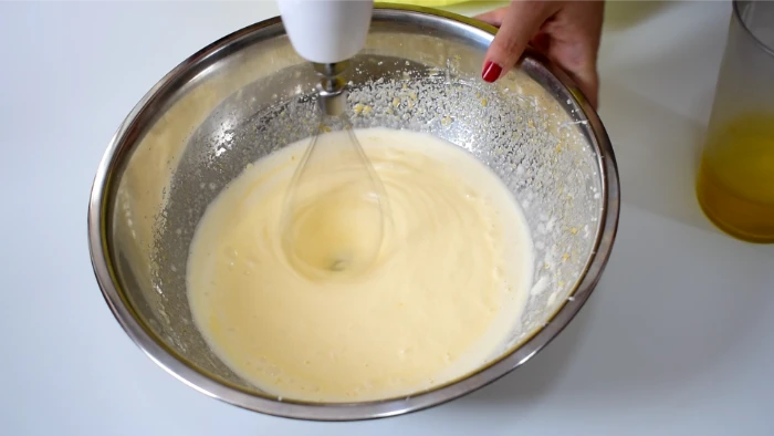 Batiendo huevos y azucar hasta blanquear para hacer bizcocho de chocolate