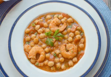 Garbanzos con langostinos servidos en plato hondo, guiso tradicional
