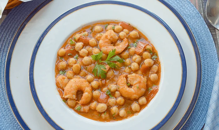 Garbanzos con langostinos servidos en plato hondo, guiso tradicional