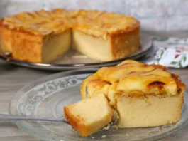 Porción de tarta de manzana con cuchara mostrando su textura cremosa. Al fondo, el resto de la tarta.