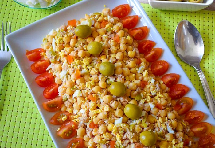 Primer plano de ensalada de garbanzos con atún, tomate cherry y aceitunas, lista para servir