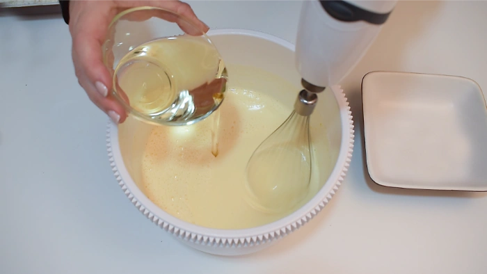 Añadiendo el aceite a los huevos blanqueados y mezclados con yogur