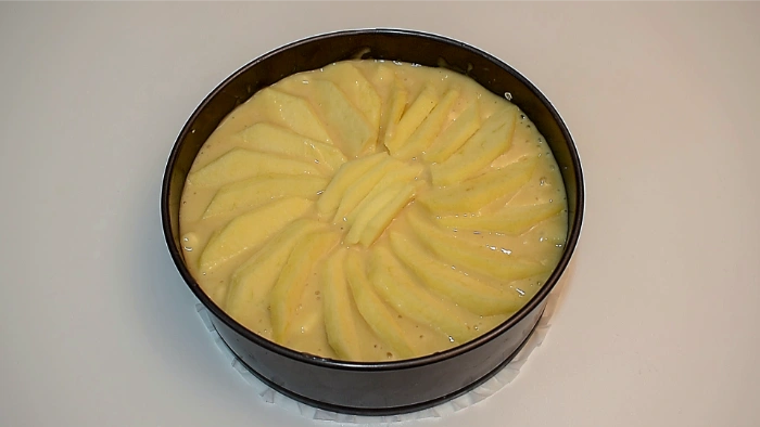 Masa del bizcocho en el molde cubierta con manzanas en la superficie