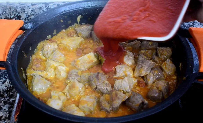 Añadiendo tomate natural al guiso de carne toledano