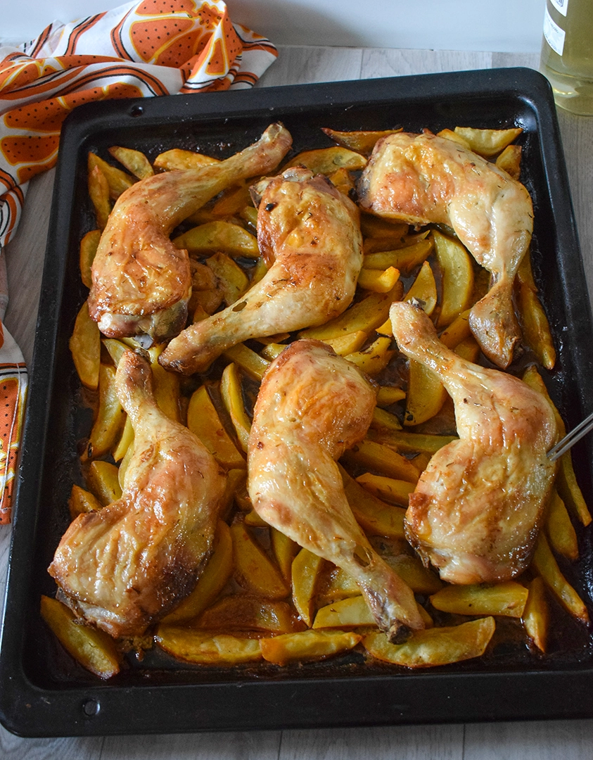 Bandeja de muslos de pollo al horno con patatas doradas