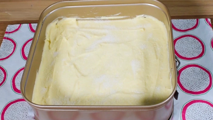 Masa del bizcocho en molde rectangular y con capa de azúcar espolvoreada encima