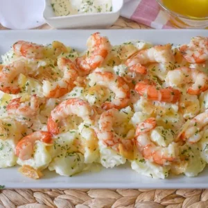 Patatas arrieras cocidas con gambas al ajillo y alioli casero servidas en fuente rectangular blanca, con cuencos de alioli y aceite de oliva al fondo