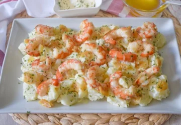 Patatas arrieras cocidas con gambas al ajillo y alioli casero servidas en fuente rectangular blanca, con cuencos de alioli y aceite de oliva al fondo