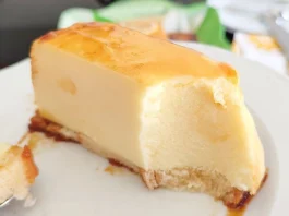 Porción de pastel de limón frío sin horno servida en plato blanco mostrando el corte cremoso, la base dorada y el caramelo que escurre