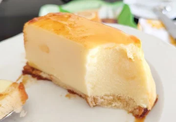 Porción de pastel de limón frío sin horno servida en plato blanco mostrando el corte cremoso, la base dorada y el caramelo que escurre