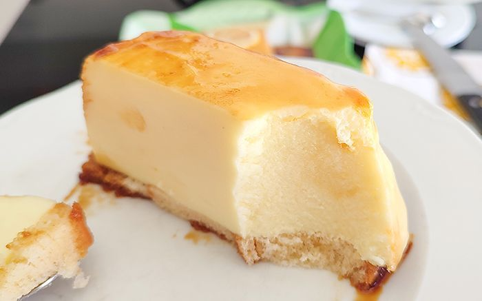 Porción de pastel de limón frío sin horno servida en plato blanco mostrando el corte cremoso, la base dorada y el caramelo que escurre