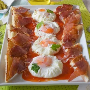 Huevos poché con jamón y tostadas servidos sobre salsa, receta casera paso a paso