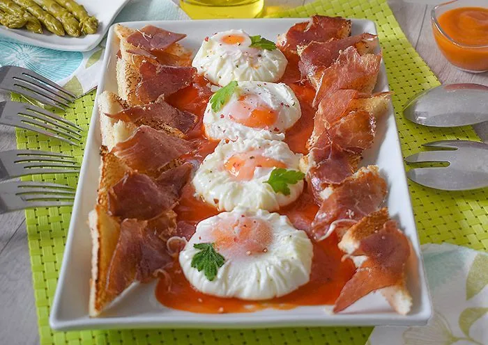 Huevos poché con jamón y tostadas servidos sobre salsa, receta casera paso a paso