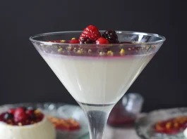 Panna cotta con coulis de frutos rojos servida en copa de cristal