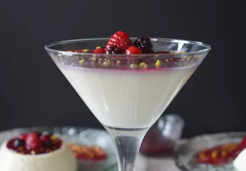 Panna cotta con coulis de frutos rojos servida en copa de cristal