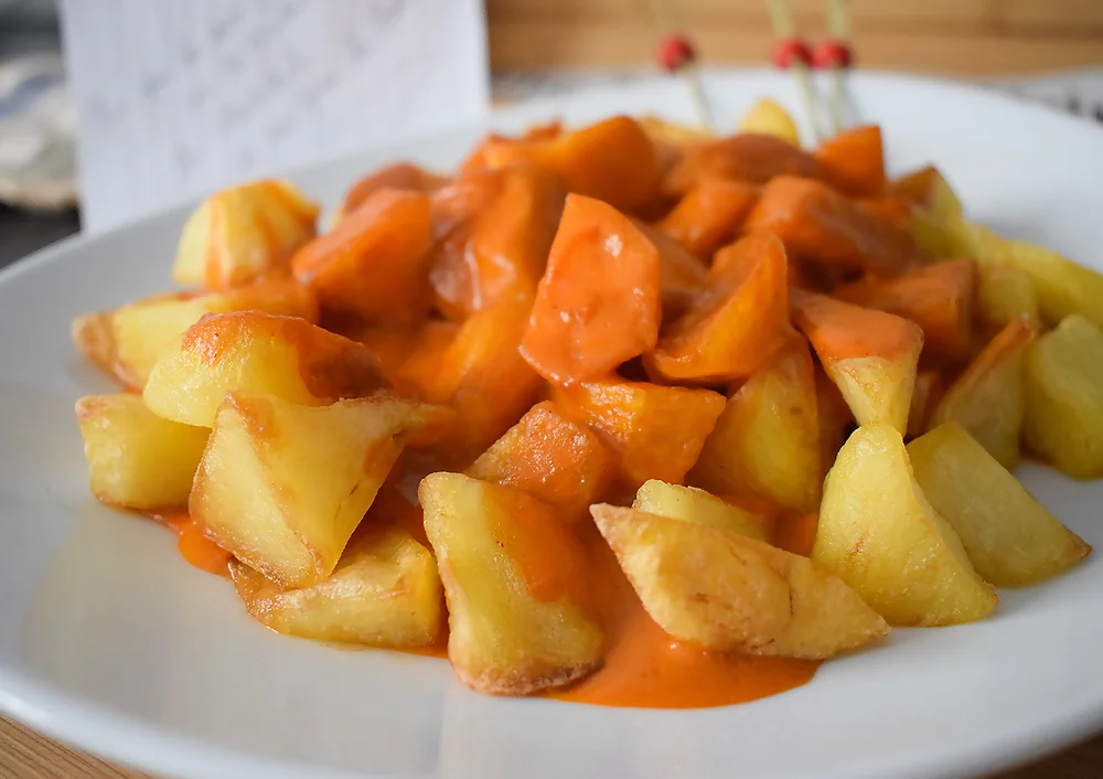 Detalle de patatas bravas recién servidas con salsa cremosa