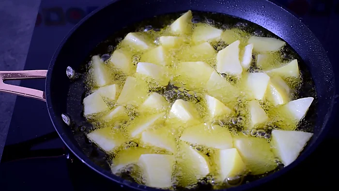 Patatas troceadas friéndose en sartén con aceite