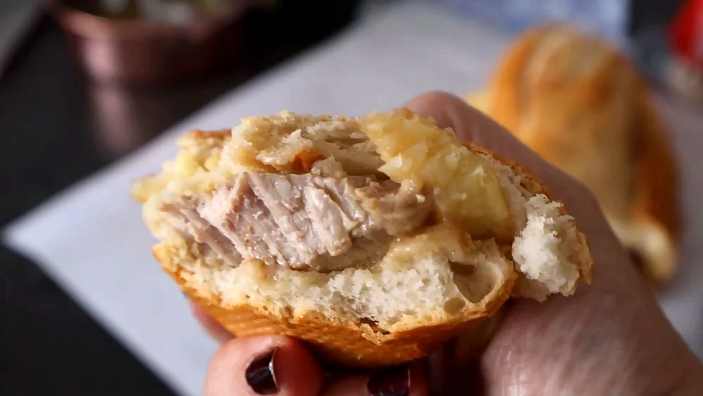 Bocadillo de solomillo al whisky con patatas, primer plano con mordisco que muestra la carne jugosa.