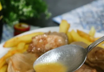 Solomillo al whisky con salsa casera servido sobre patatas fritas.