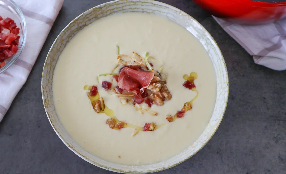 Vichyssoise casera servida fría con virutas de jamón, nueces y aceite de oliva