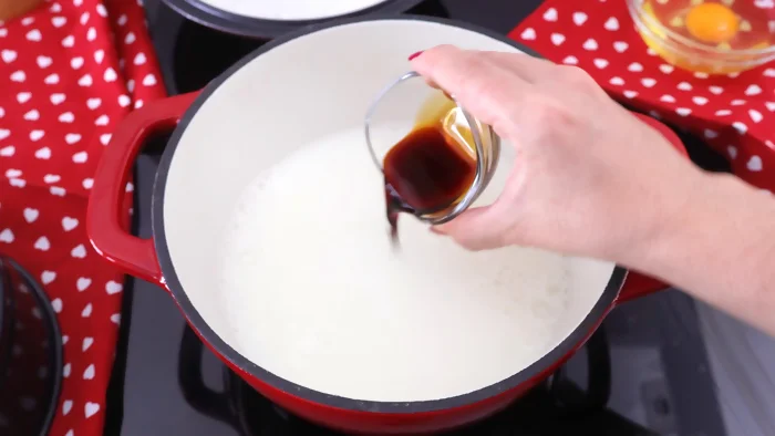 Leche calentándose en una cacerola con extracto de vainilla para hacer crema pastelera