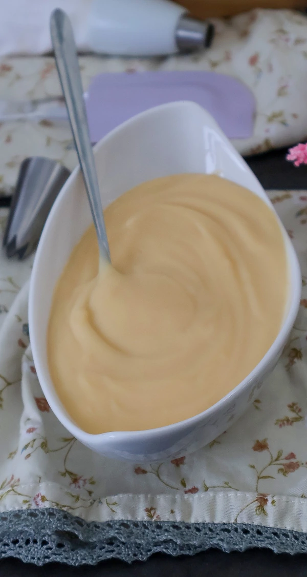 Crema pastelera casera con textura cremosa y sin grumos en cuenco blanco con cuchara